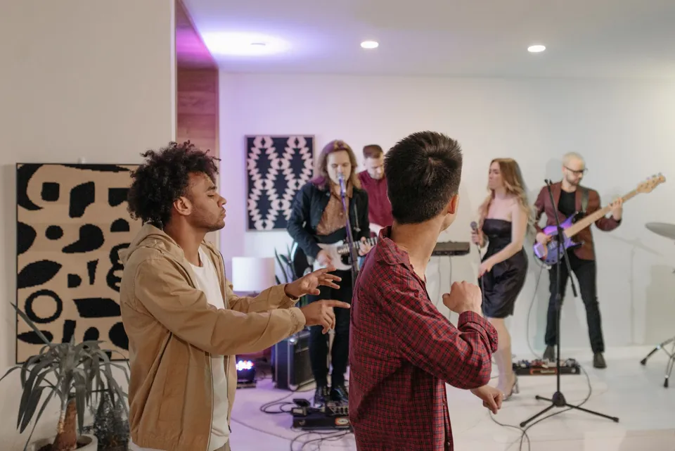 People dancing while a band plays guitars and sings indoors