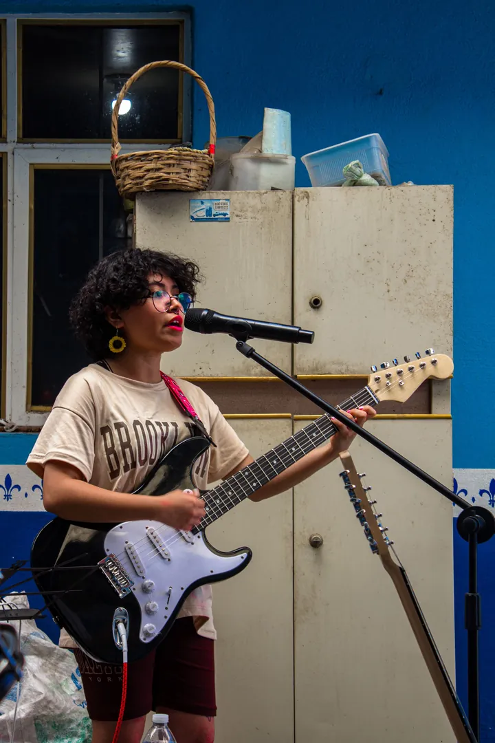 A performer singing into a microphone while playing an electric guitar