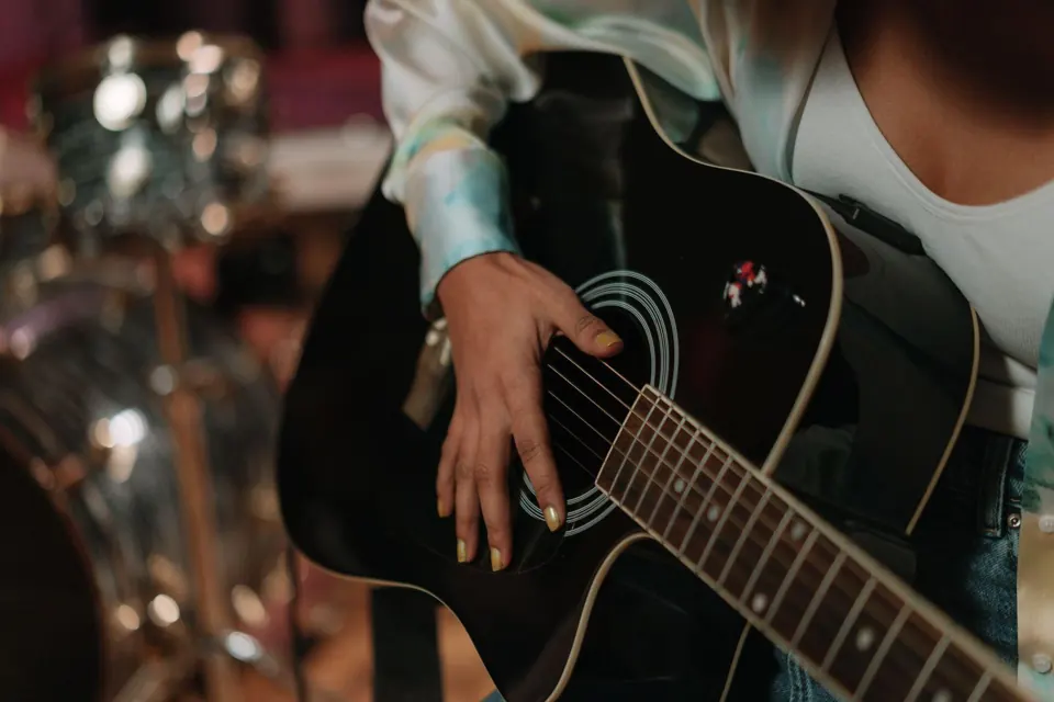 Close-up of a hand resting on an acoustic guitar