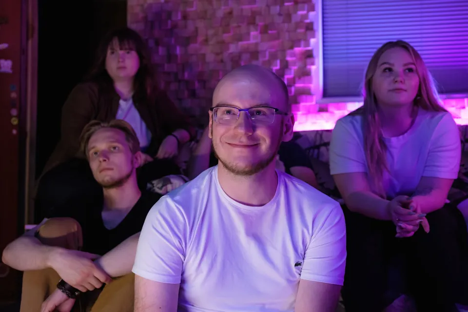 Adults seated together listening under colorful indoor lighting